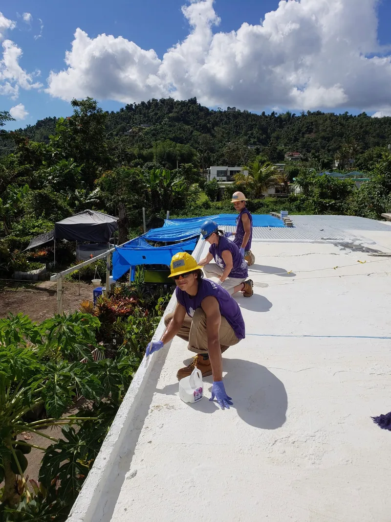 The Color Love Painting team paints a roof in Puerto Rico during a volunteer effort after a devastating hurricane